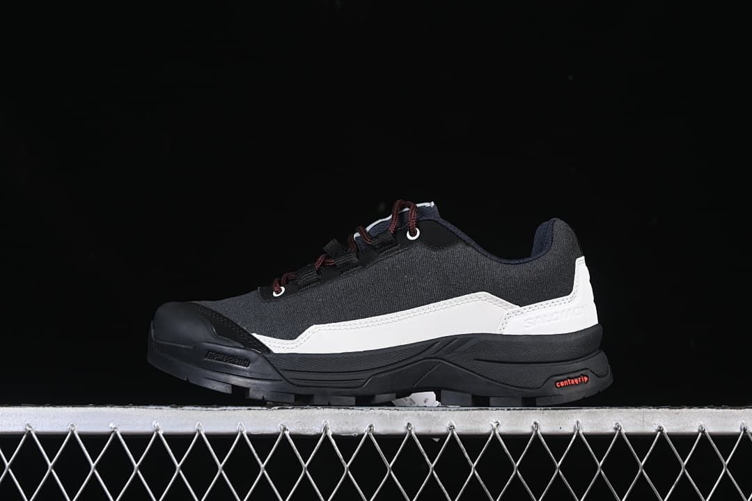 Side view of the shoe showing its black upper, white panel and rugged outsole.