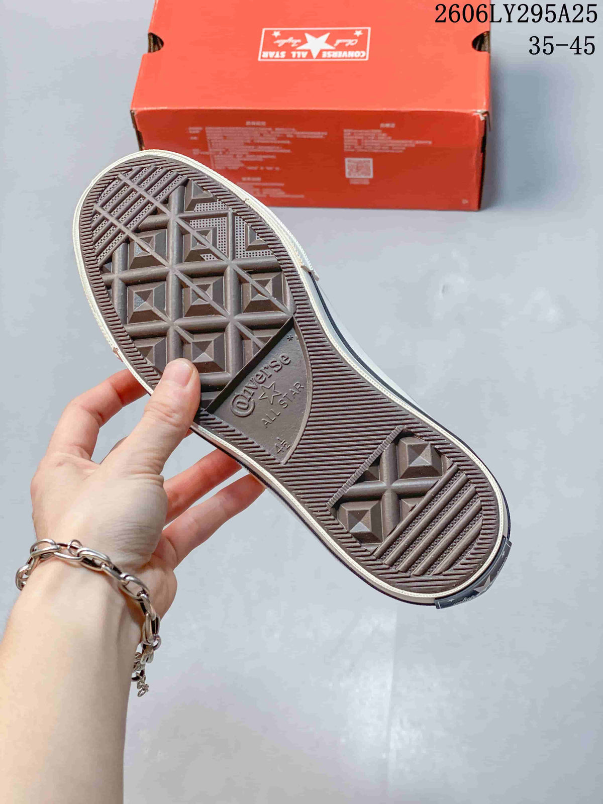 Outsole view of a Converse All Star sneaker, with a red shoe box in the background