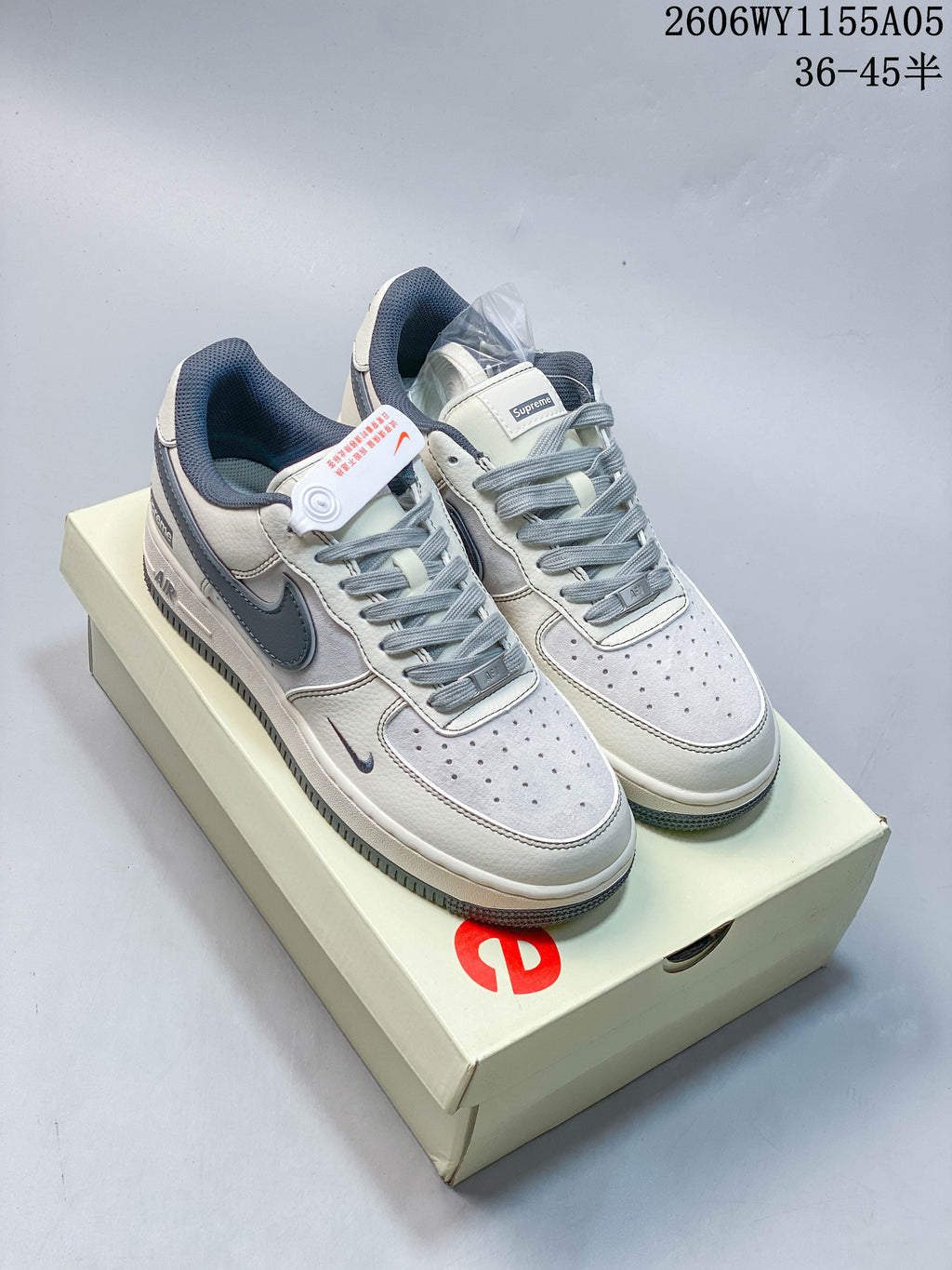 Pair of white and slate-blue Nike Air Force 1 Low sneakers with Supreme branding on a box