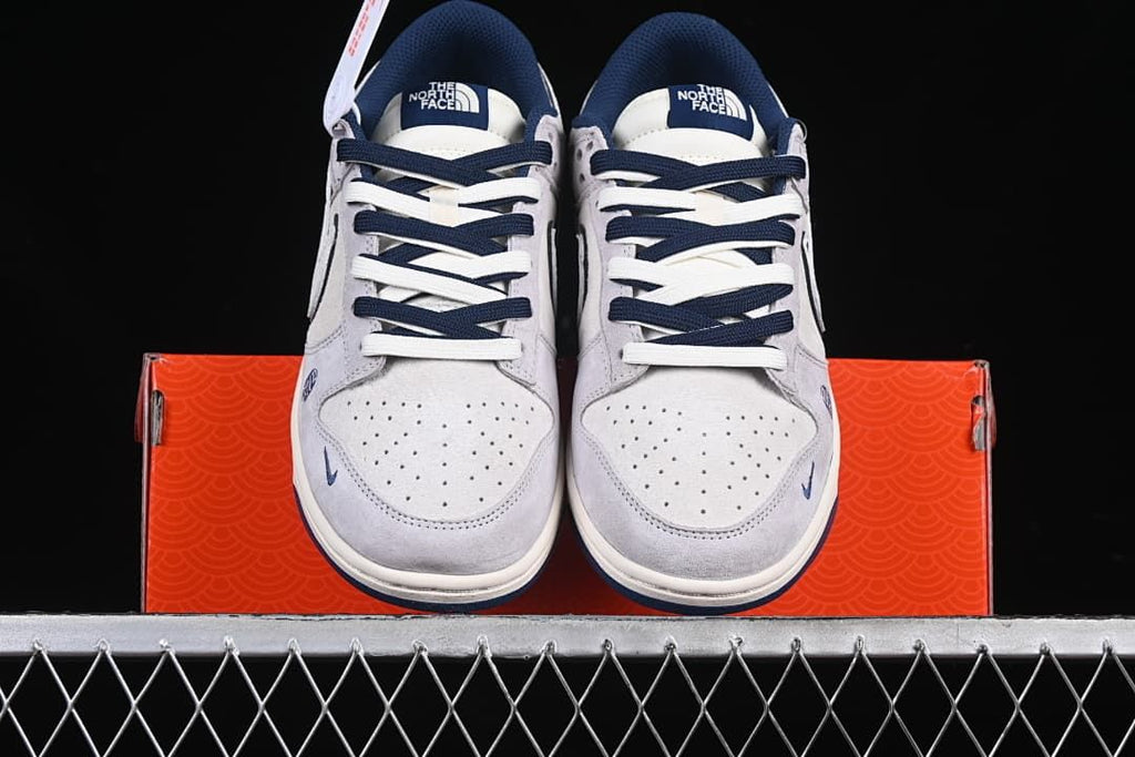 Front view of both sneakers resting on the orange patterned shoebox.