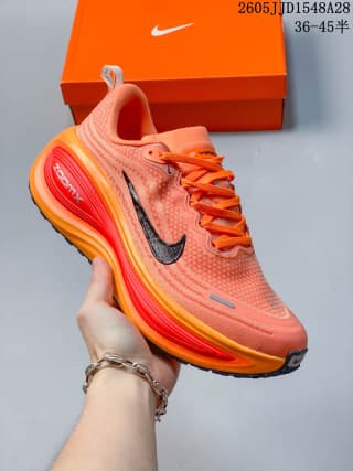 Orange Nike Vomero Plus shoe with dark swoosh and red-orange sole accents.