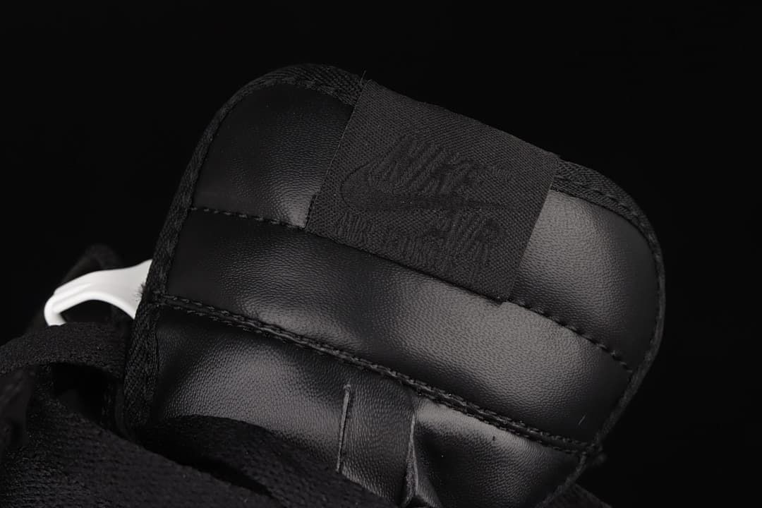 Close-up of the tongue and woven label on the black sneaker.