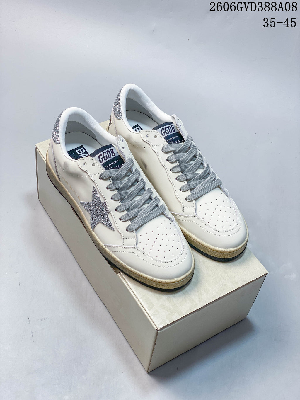 Pair of white Golden Goose Super-Star style sneakers with silver glitter star details and gray laces