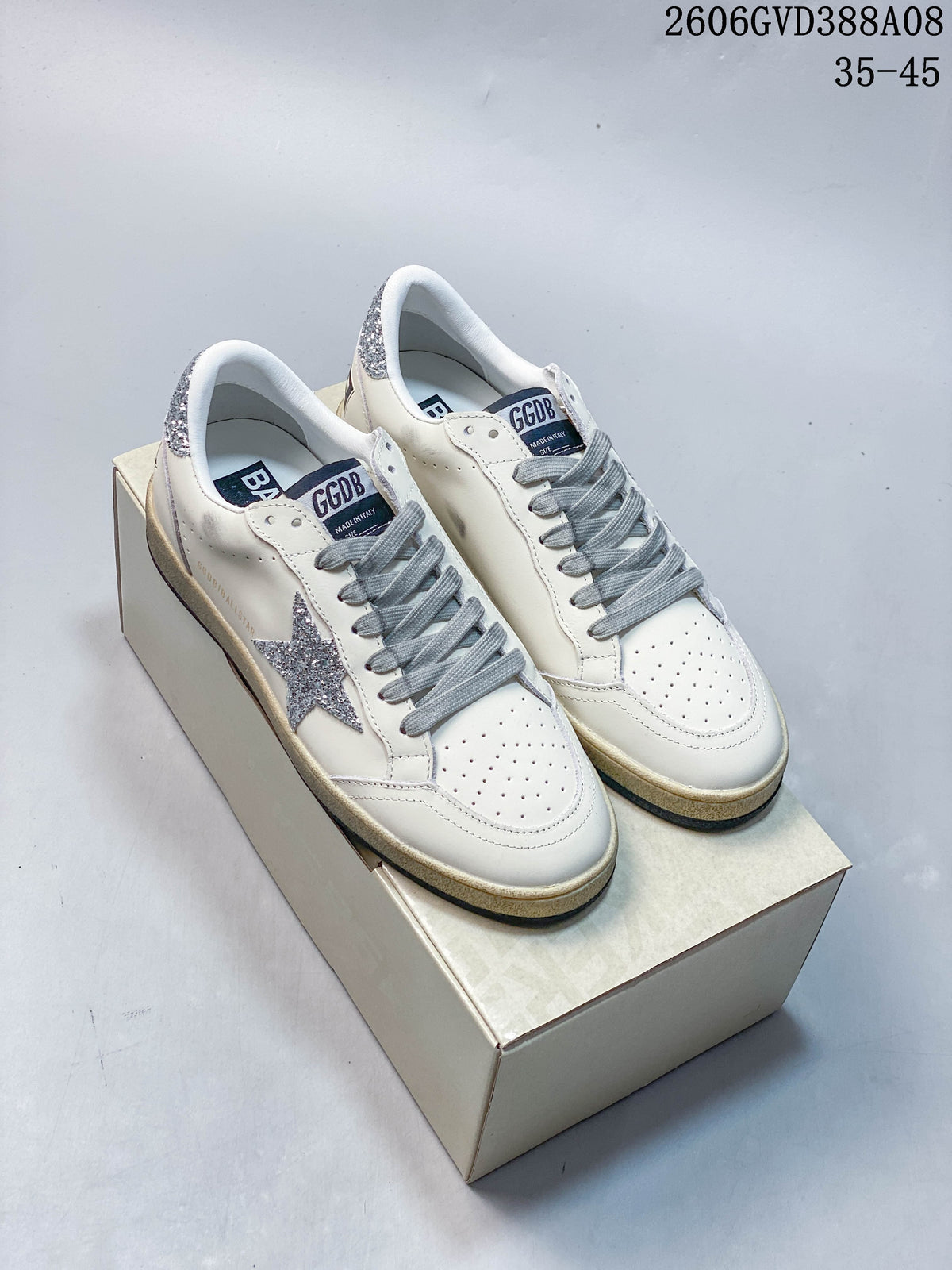 Pair of white Golden Goose Super-Star style sneakers with silver glitter star details and gray laces