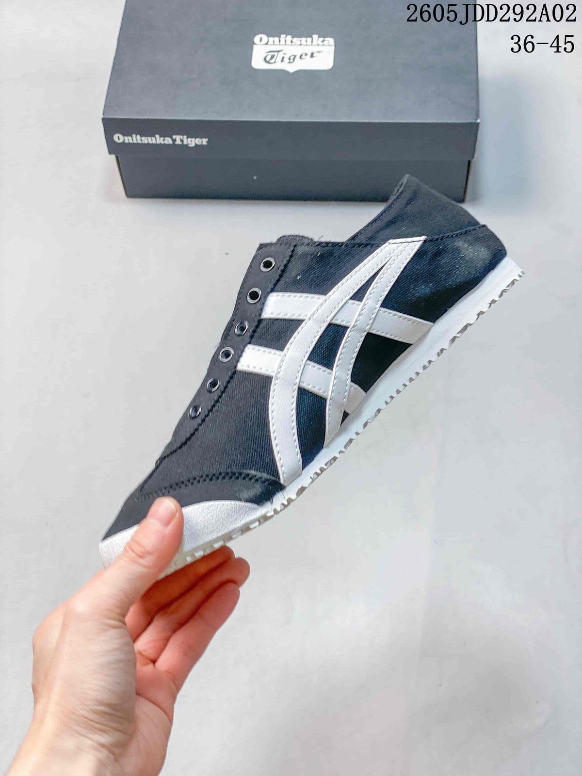 Side profile of a charcoal Onitsuka Tiger sneaker with white stripes and no laces