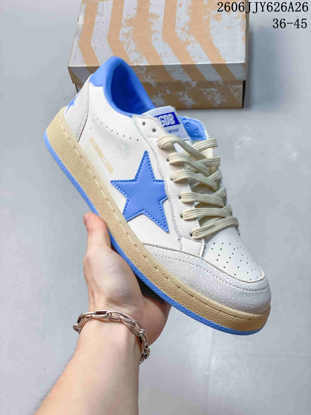 White low-top sneaker with a blue star detail, blue collar lining, and a distressed-look beige sole.