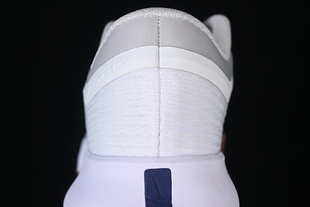 Rear view of the shoe showing the white mesh-look upper and gray heel detail.
