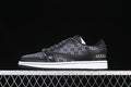 Side view of a black low-top sneaker with dark monogram-style panels and a white midsole