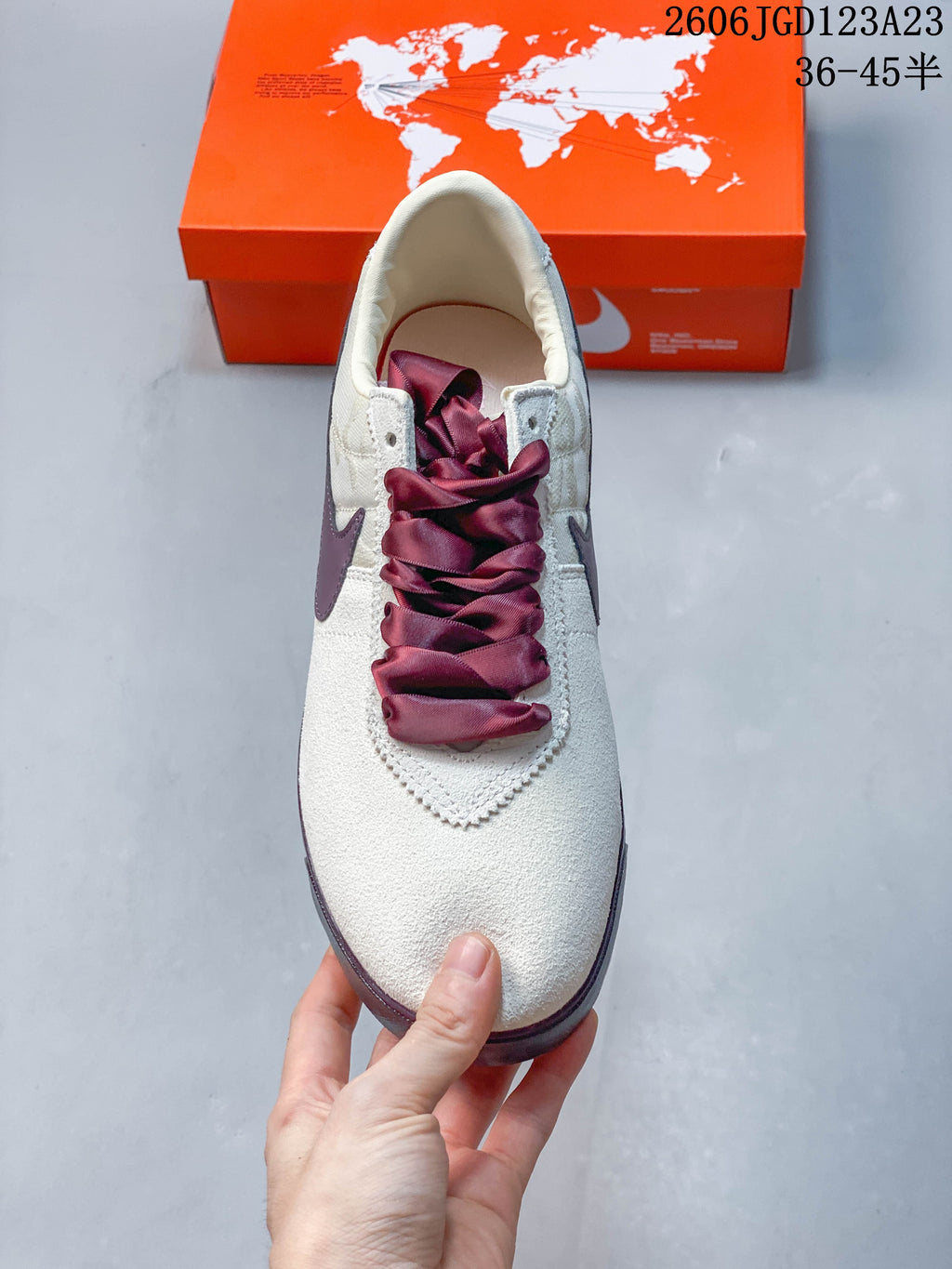 Top view of the sneaker showing wide plum-colored laces and an off-white upper
