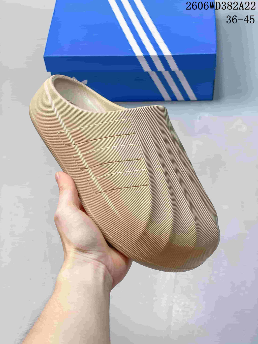 Angled side view of a beige clog with three-bar detailing