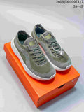 Pair of olive-green and gray Nike Free 2025 low-top shoes on an orange shoe box.