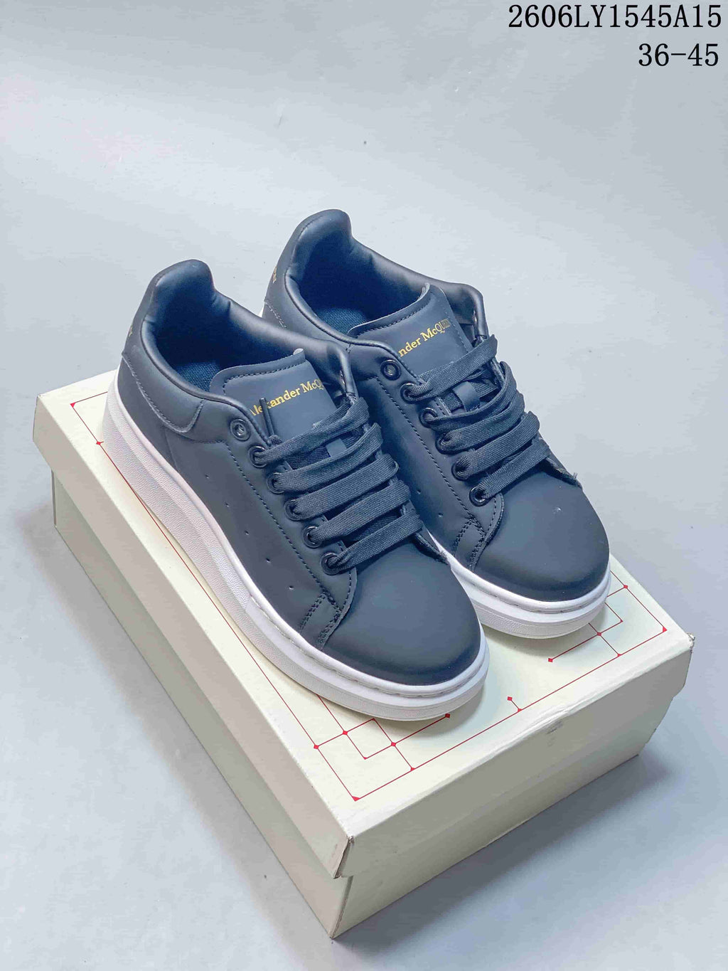 Dark grey low-top sneakers with a white sole, shown beside a white pair with a grey heel panel.