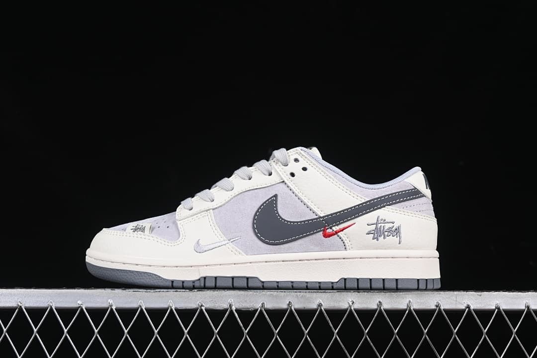 Side view of off-white and grey Nike Dunk Low sneakers with dark grey Swoosh and red accent