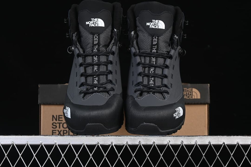 Front view of the pair of black mid-height hiking boots on a box