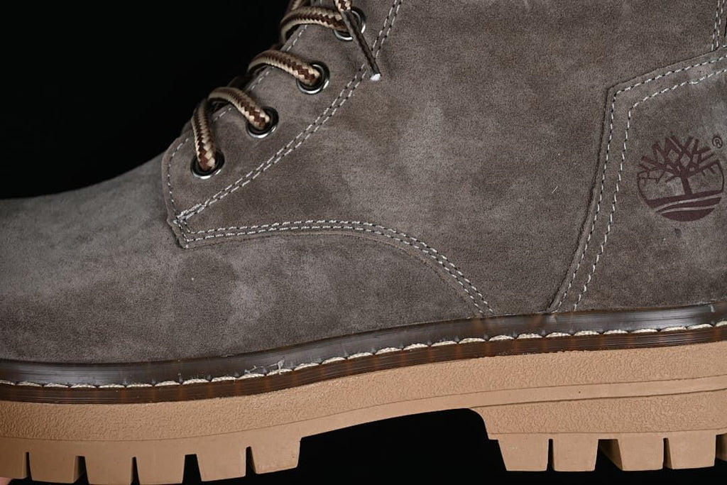 Close-up of the gray boot upper, contrast stitching and lace hooks.