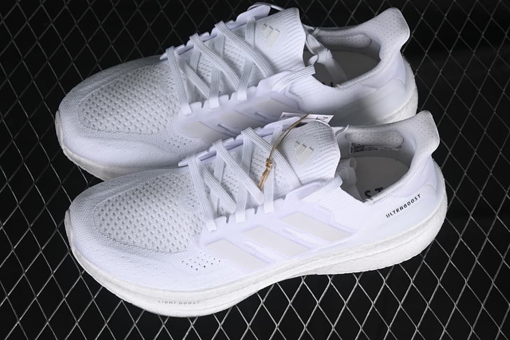 Pair of white Adidas Ultraboost 5 shoes viewed from above.