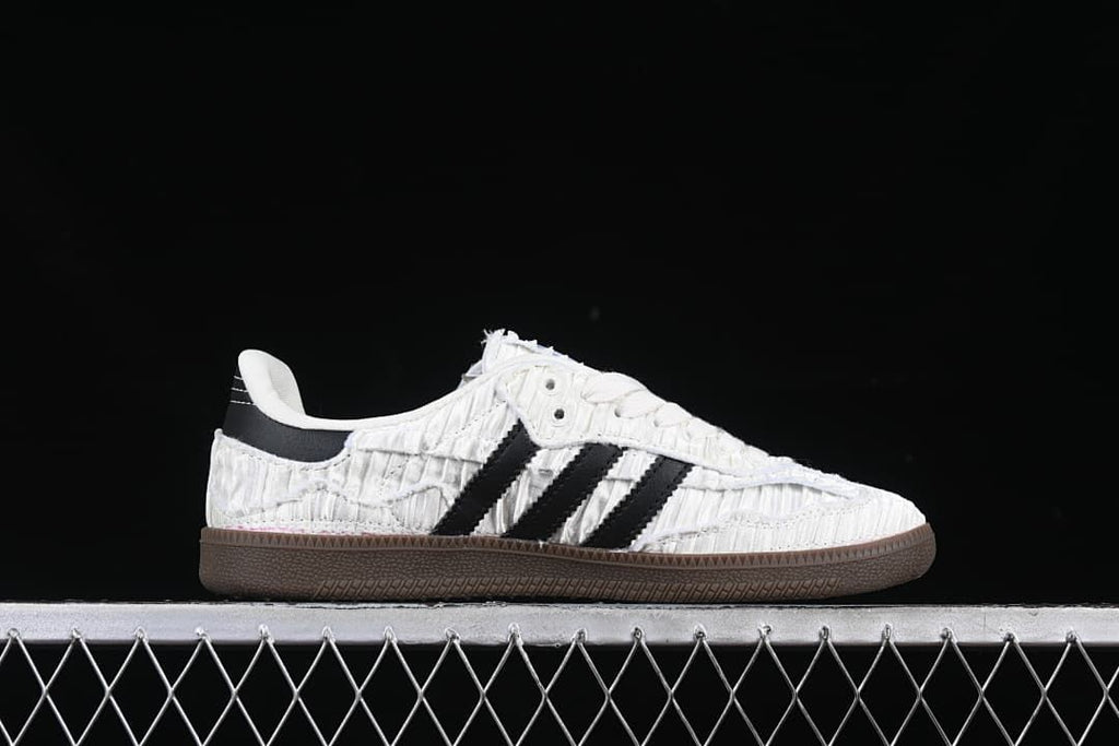 Side profile of a white sneaker with black stripes and a dark brown sole