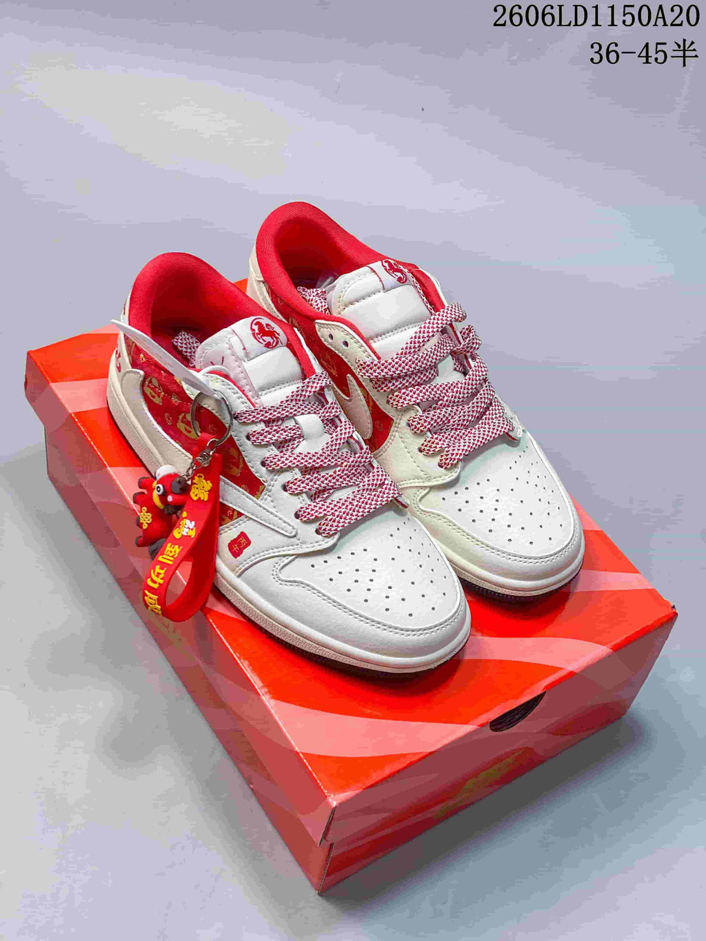White low-top sneakers with red trim, patterned laces, and red decorative accents.