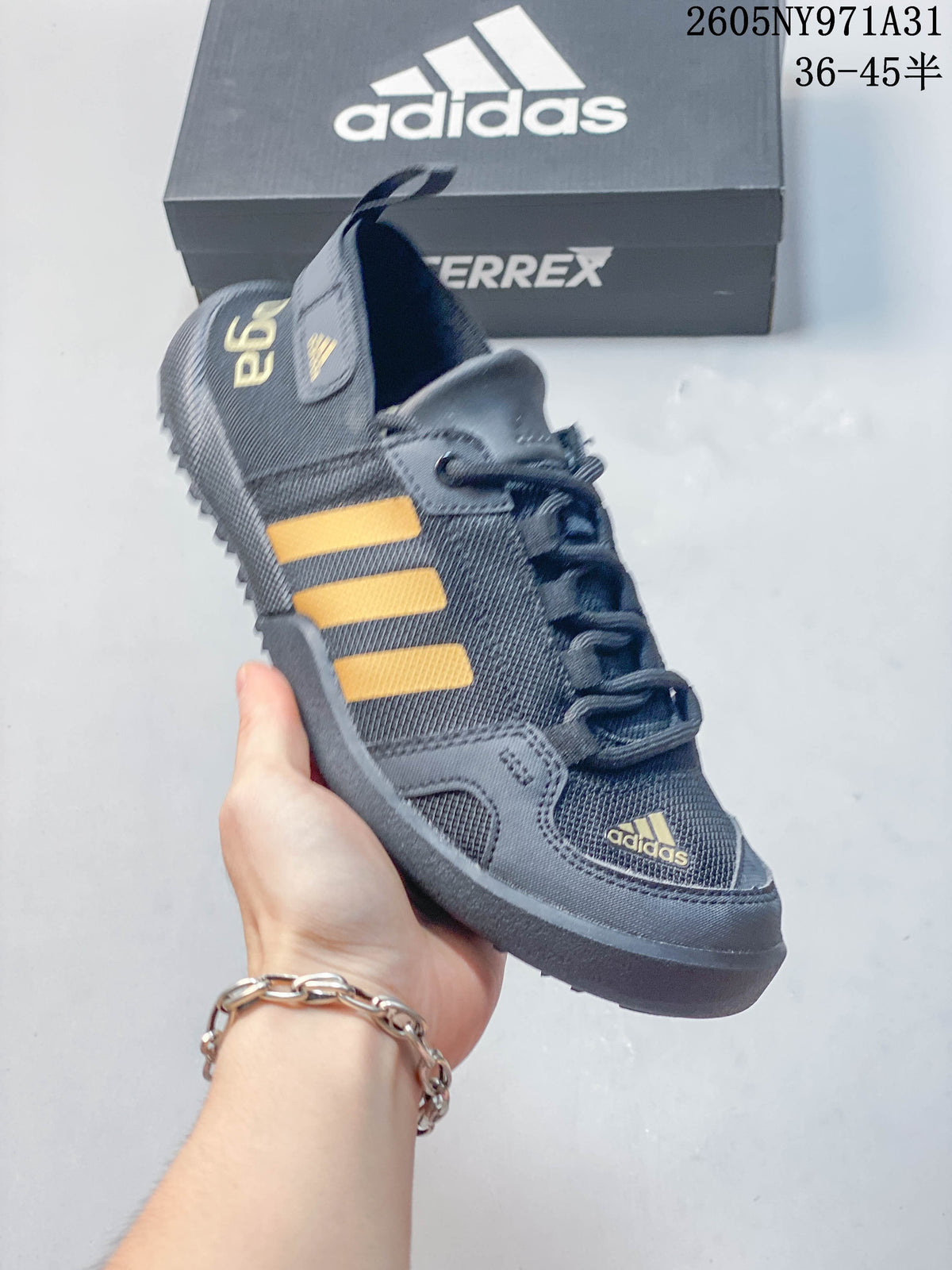 Angled view of a dark gray outdoor shoe with yellow-orange stripes