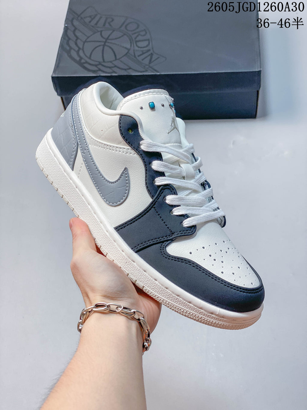 Angled side view of a white, dark blue, and gray Air Jordan 1 Low sneaker