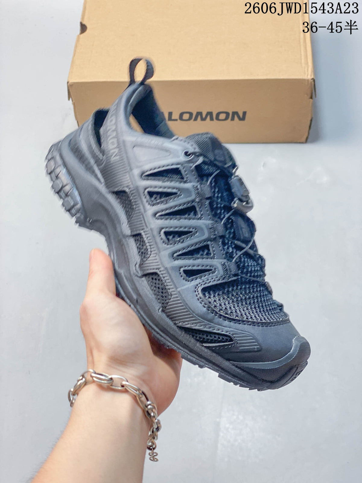 Angled side view of a dark gray Salomon shoe with open mesh panels and a lugged outsole.