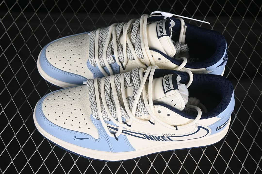 Top view of a pair of off-white and light blue low-top sneakers showing perforated toe panels, patterned laces, navy collars, and Supreme tongue labels.