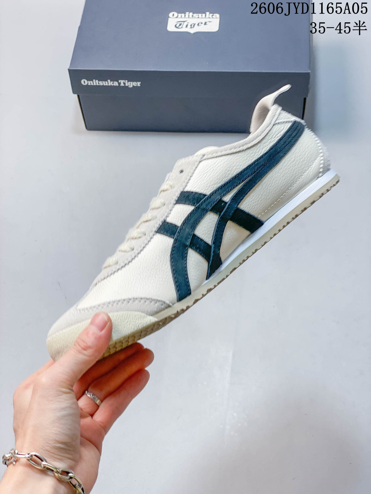 Side view of an ivory-colored Onitsuka Tiger Mexico 66 sneaker with dark navy stripes.