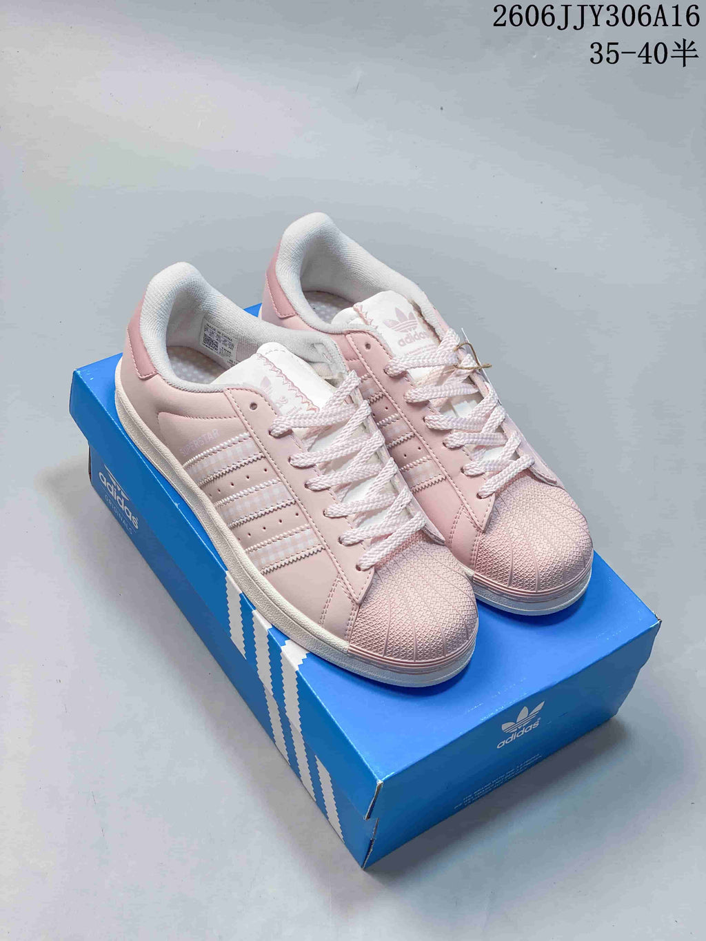 Pair of pale pink Adidas Superstar II sneakers on a blue shoebox