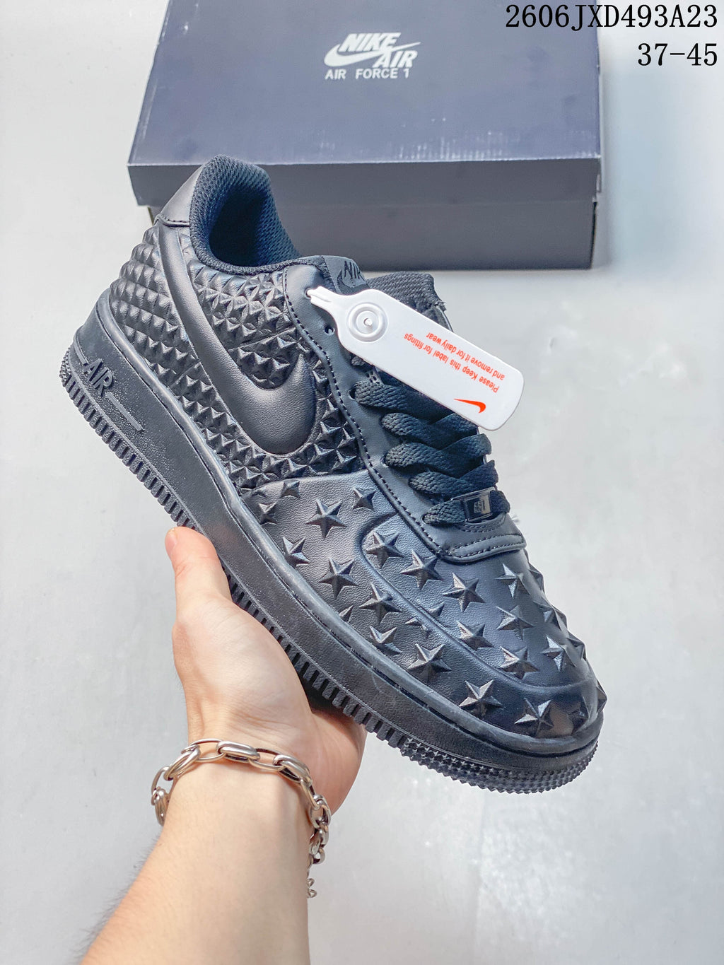 Angled side view of a dark sneaker with raised star motifs and tonal Swoosh