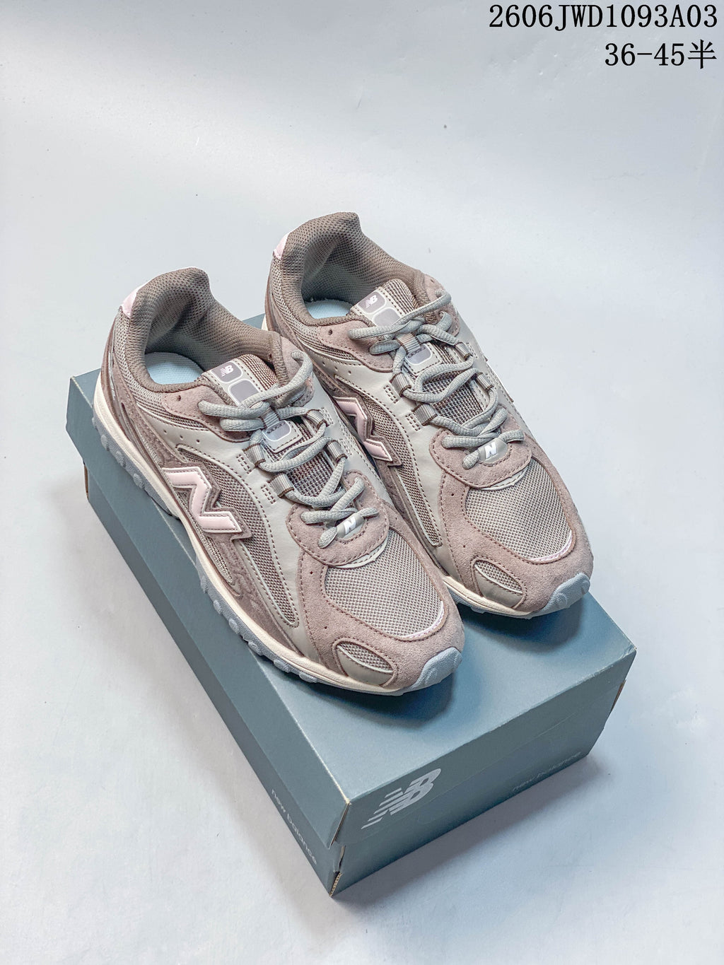 Pair of gray-brown New Balance 204L low-top sneakers with pale pink accents on a shoe box