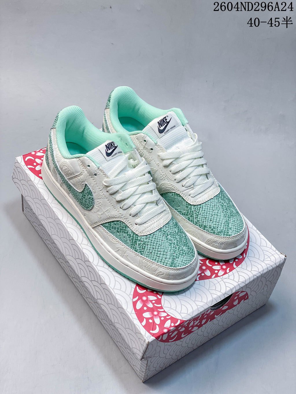 Pair of white and mint-green Nike Court Vision Low sneakers with snake-scale patterned panels on a Year of the Snake 2025 box
