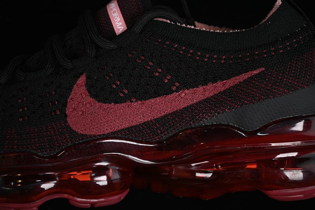Close-up of the black knit upper, dark red Swoosh, and translucent red sole