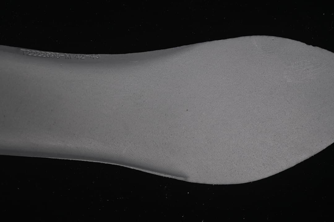 Close-up of a grey shoe component with a printed code and size range.