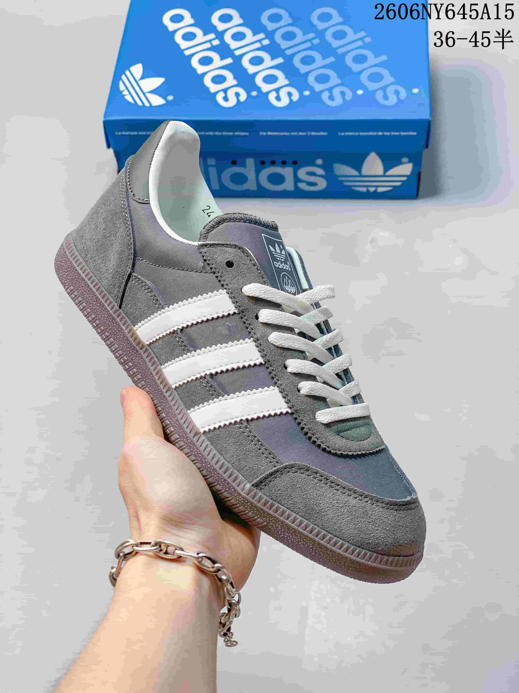 Side view of a grey adidas Handball Spezial sneaker with white stripes, laces, and a gum-style sole.