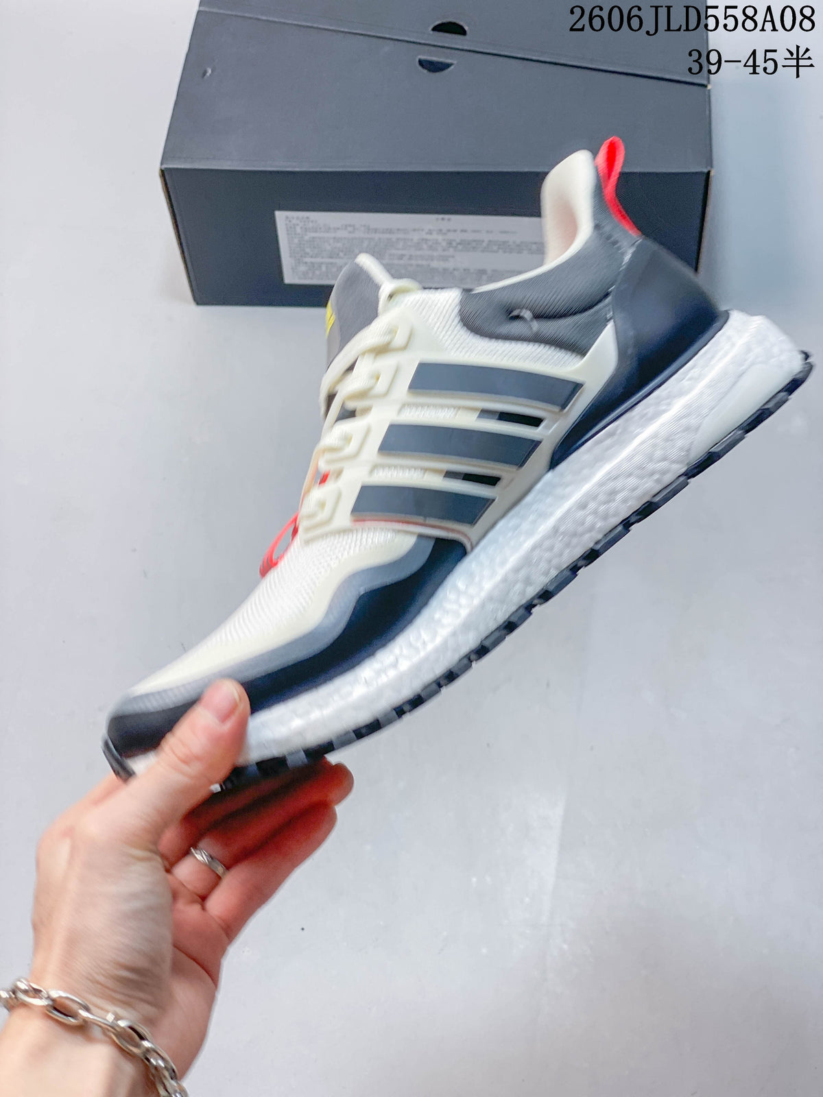 Side view of a white and grey Adidas sneaker with navy overlays and a lugged outsole.