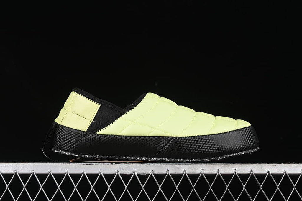 Side profile of the yellow slip-on shoe with a black patterned sole.