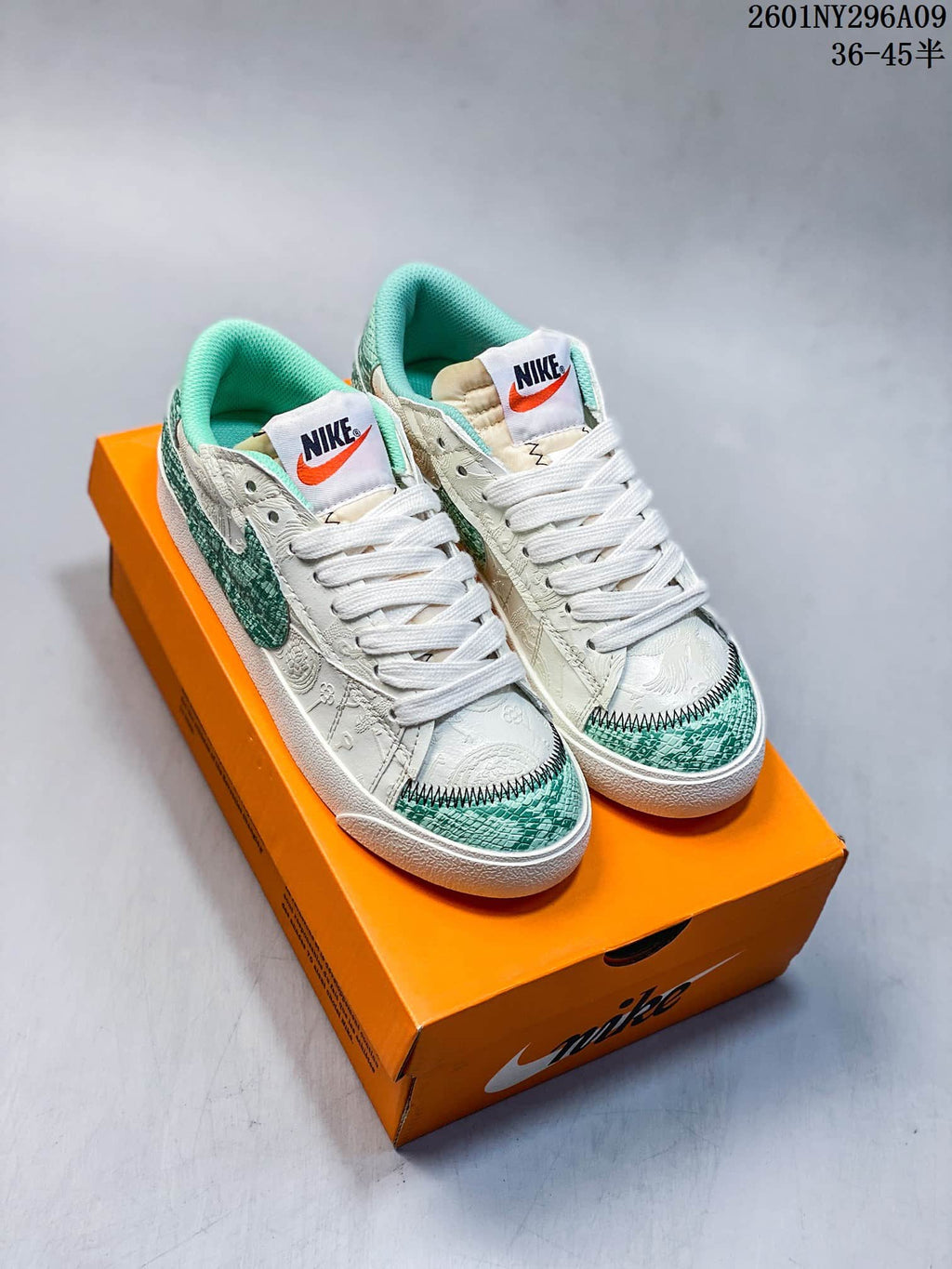Pair of white and green Nike Blazer Low '77 Jumbo sneakers displayed on an orange shoebox.