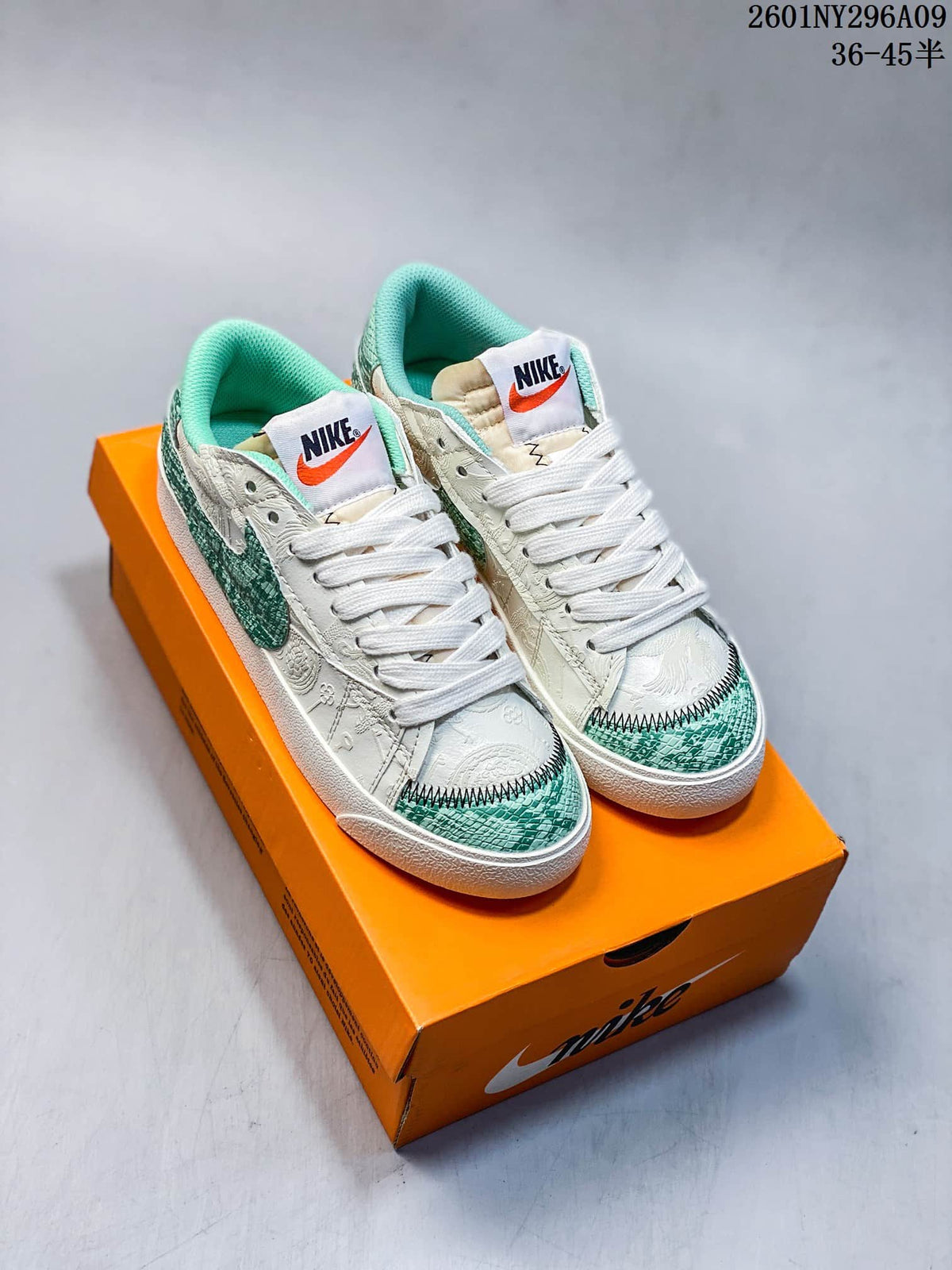 Pair of white and green Nike Blazer Low '77 Jumbo sneakers displayed on an orange shoebox.