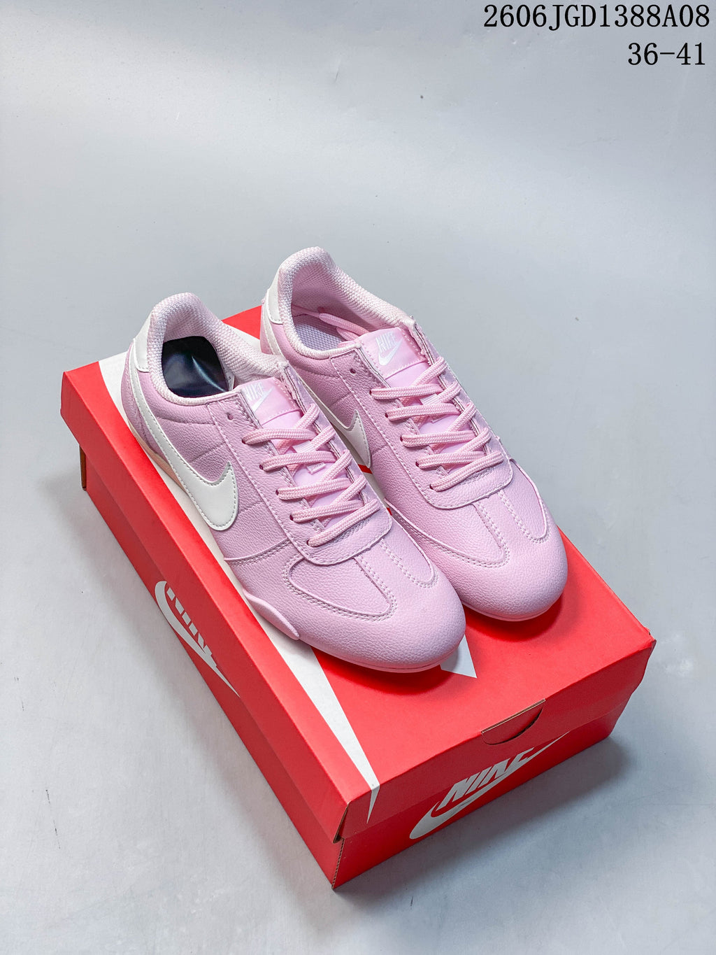 Pair of pink Nike Moon Shoe OG Summit low-top sneakers with white Swoosh details on a red box