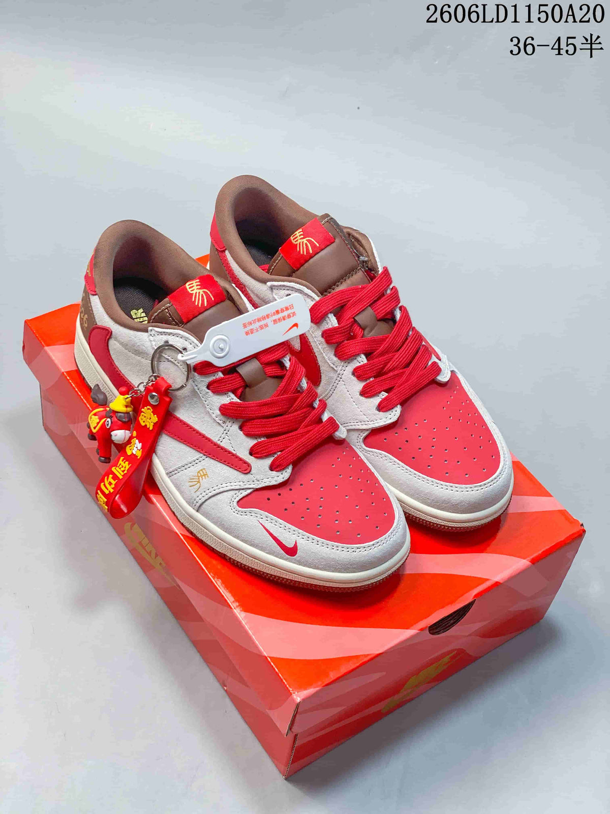 Pair of red, light grey, and brown Air Jordan 1 Low sneakers with decorative tags, shown on a red box.