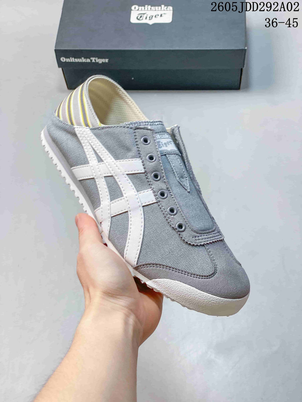 Angled view of the gray slip-on sneaker with white side stripes