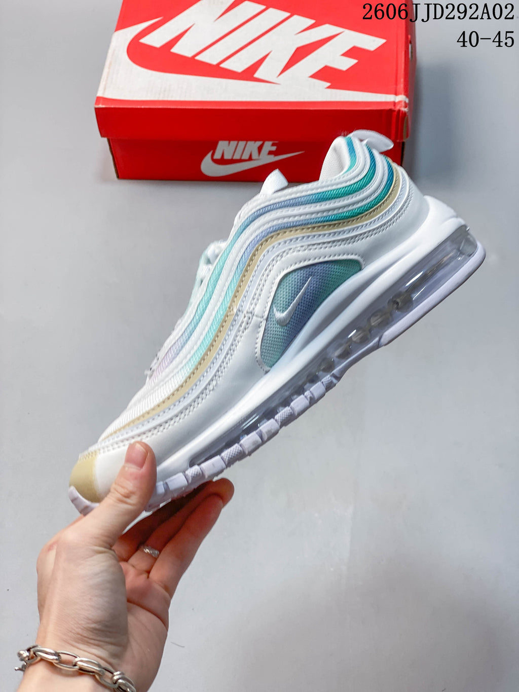 Side view of a Nike Air Max 97 sneaker with white, aqua, and pale gold wavy panels
