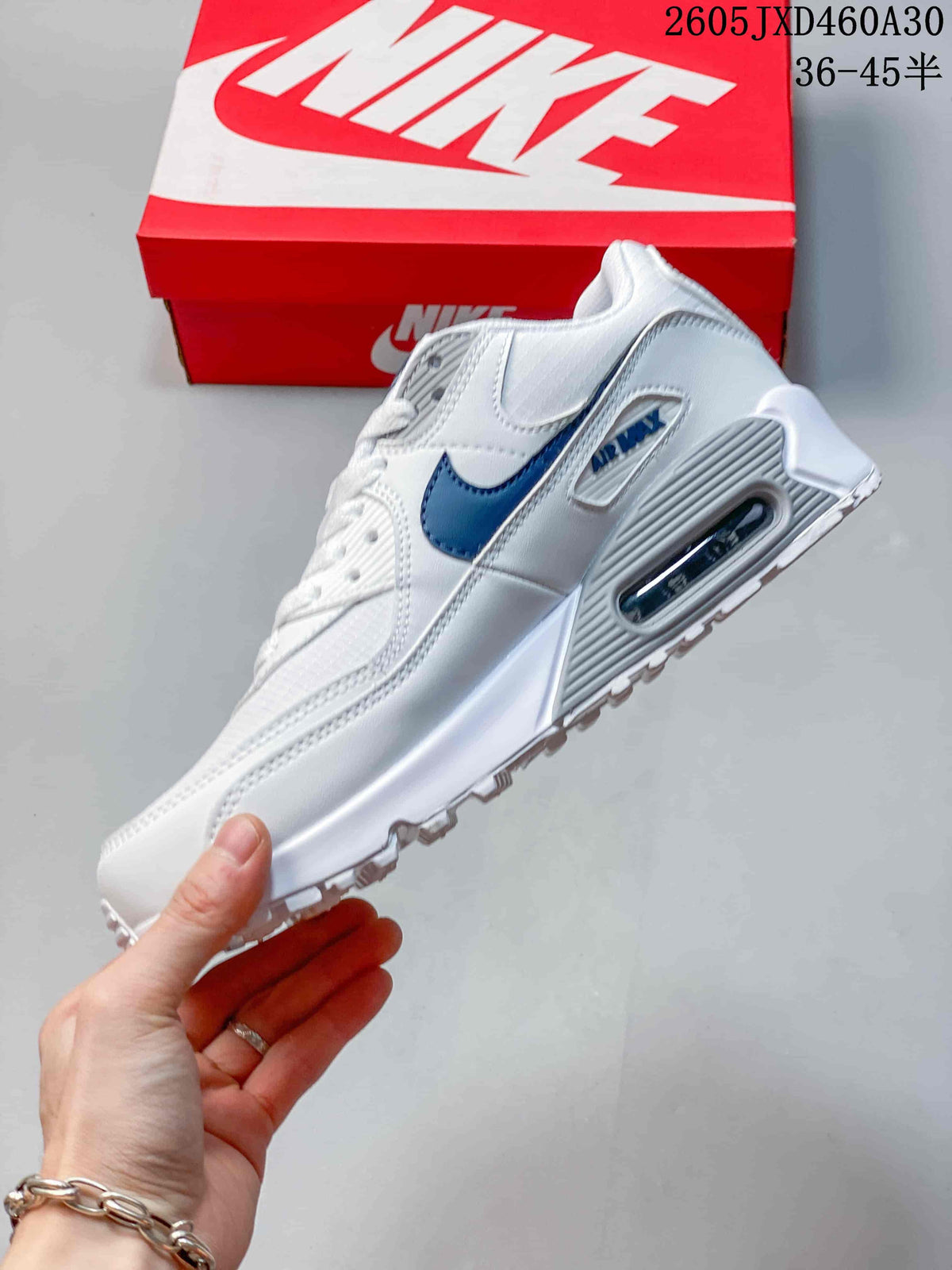 Side view of a white Nike Air Max 90 sneaker with blue accents and a visible heel Air unit