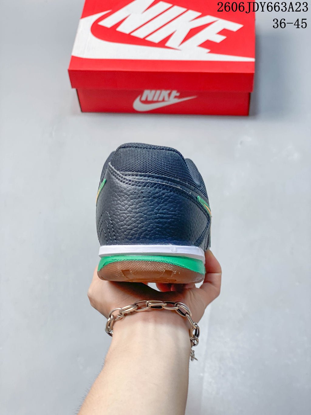 Rear view of the sneaker showing a dark upper and green and white heel details