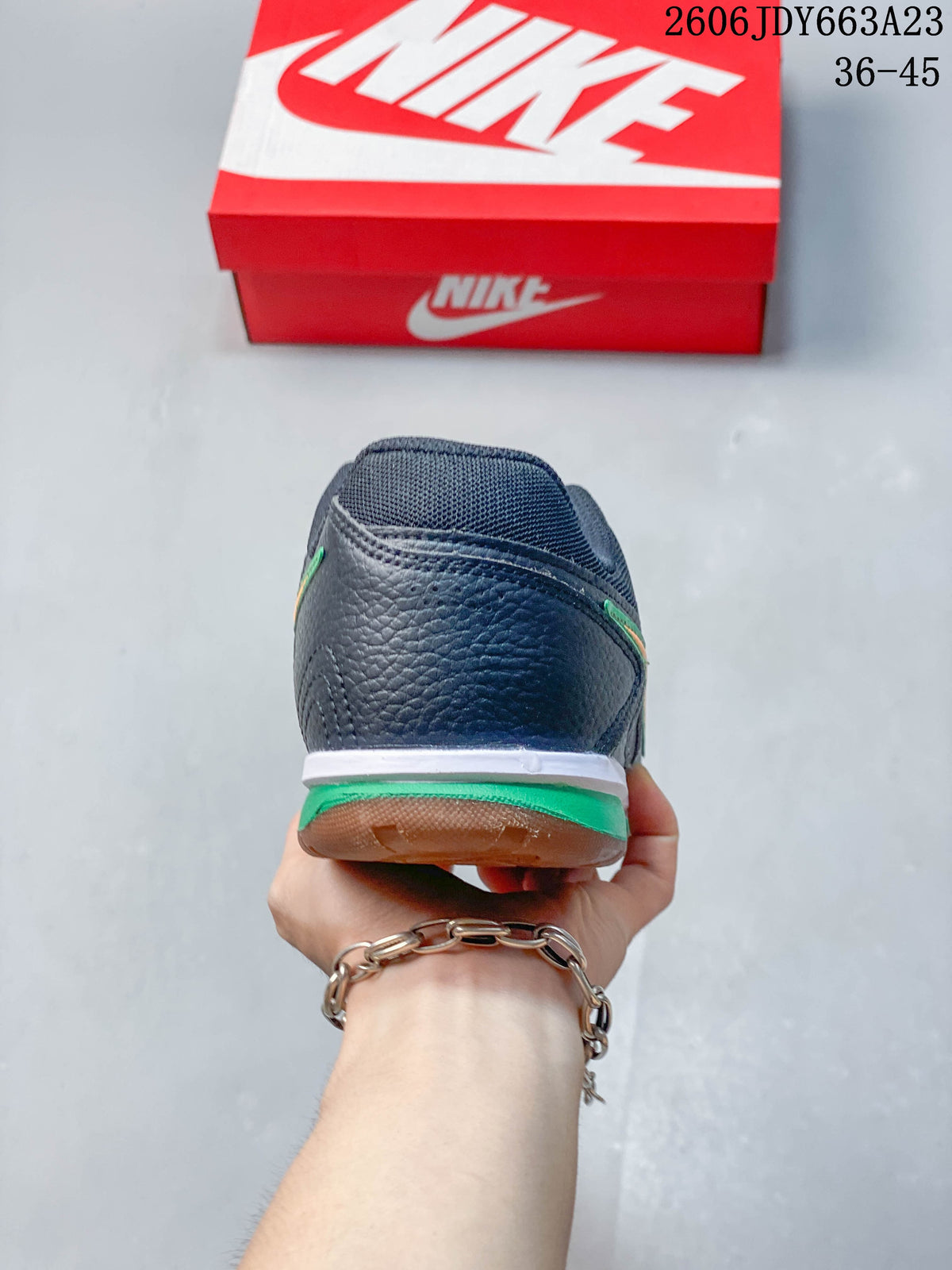 Rear view of the sneaker showing a dark upper and green and white heel details