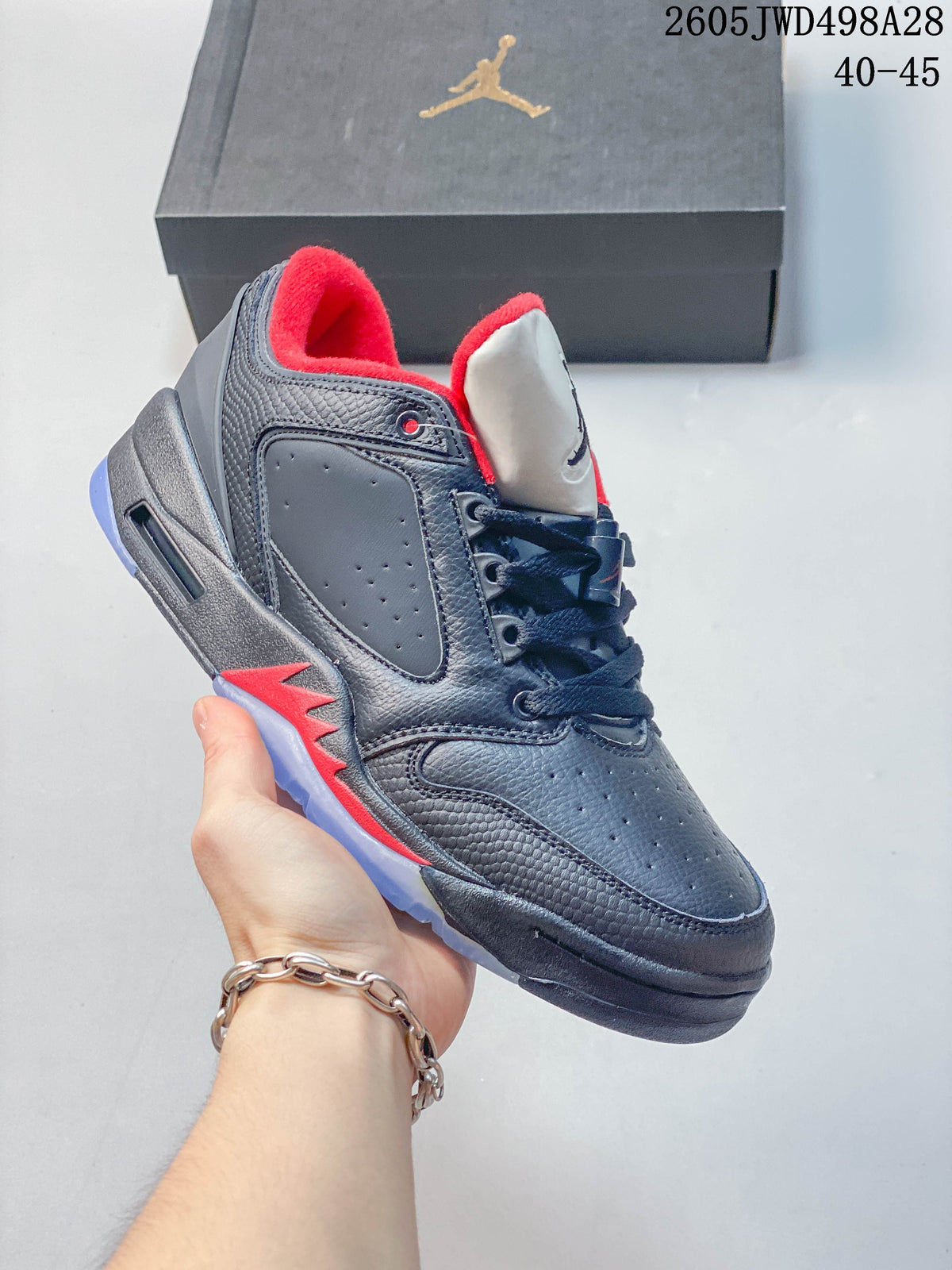 Angled side view of a dark Jordan low-top sneaker with red trim and a light-colored outsole.
