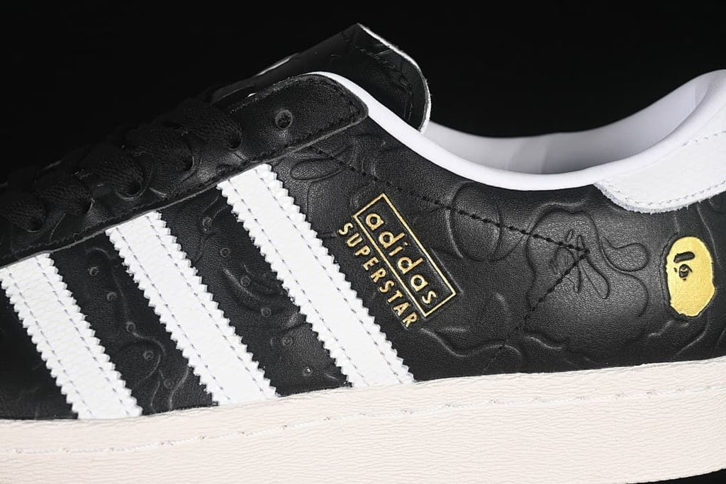 Close-up of the black embossed upper, white stripes, and gold-tone branding