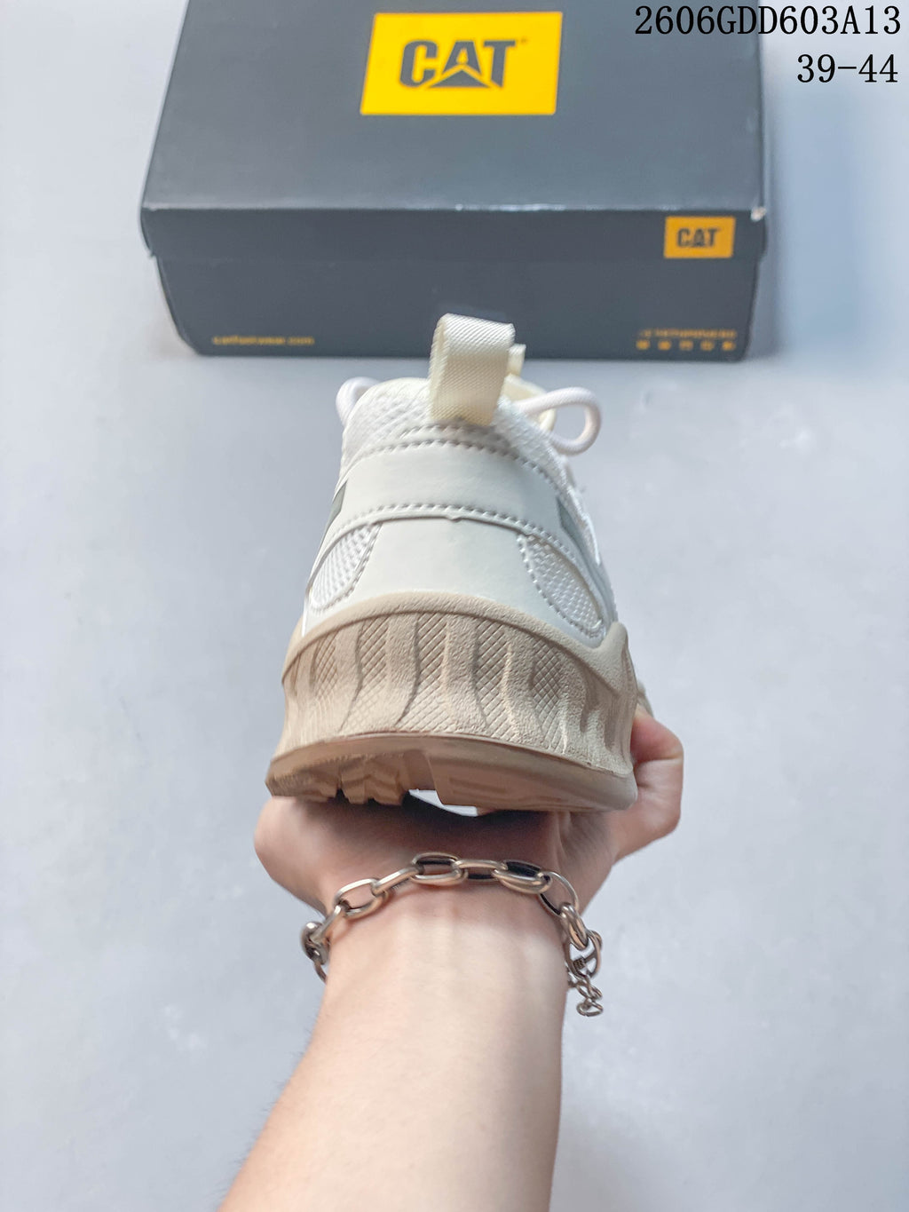 Rear view of a white and beige CAT sneaker with heel pull tab