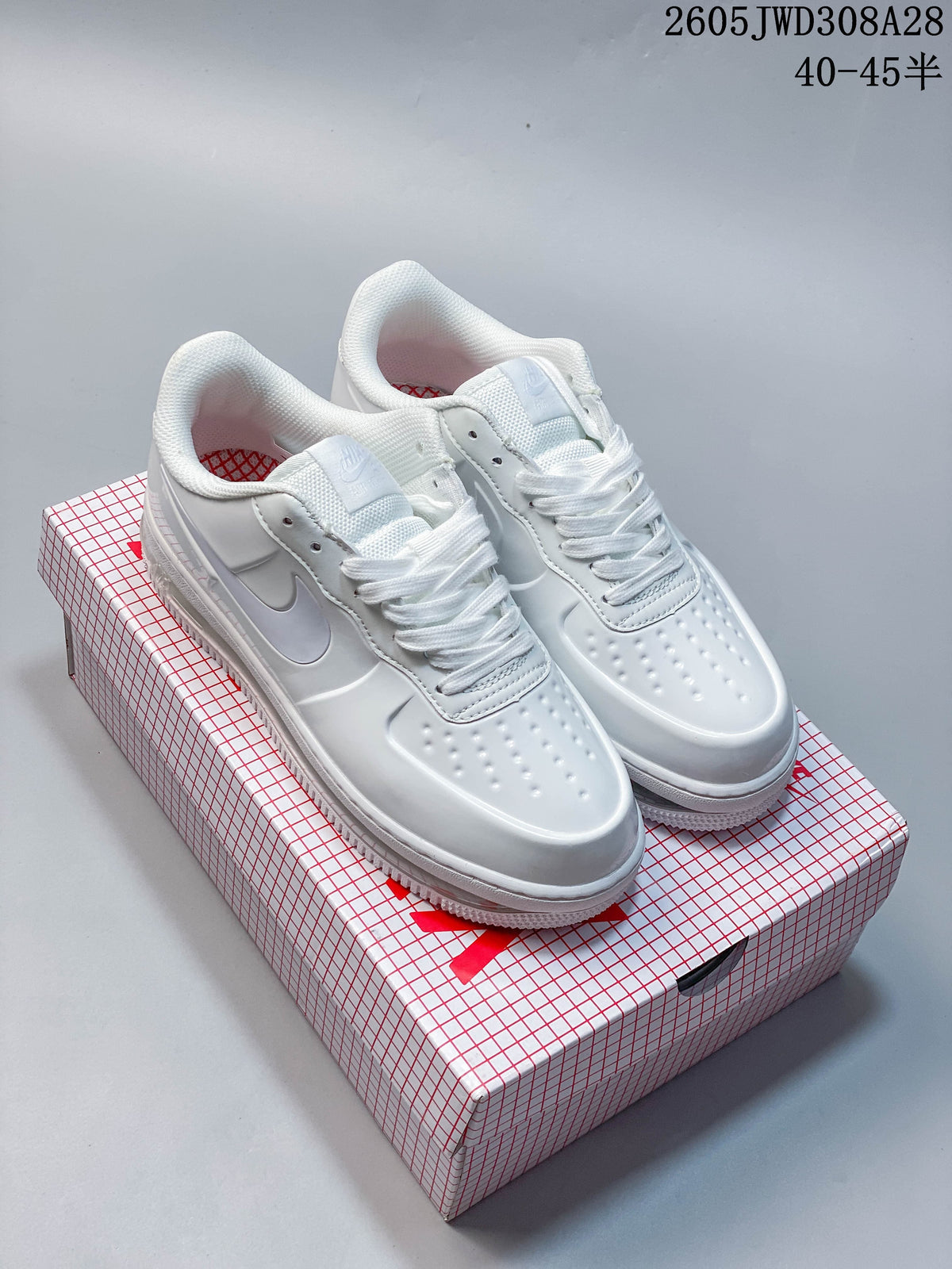 Pair of white Nike low-top sneakers displayed on a patterned box