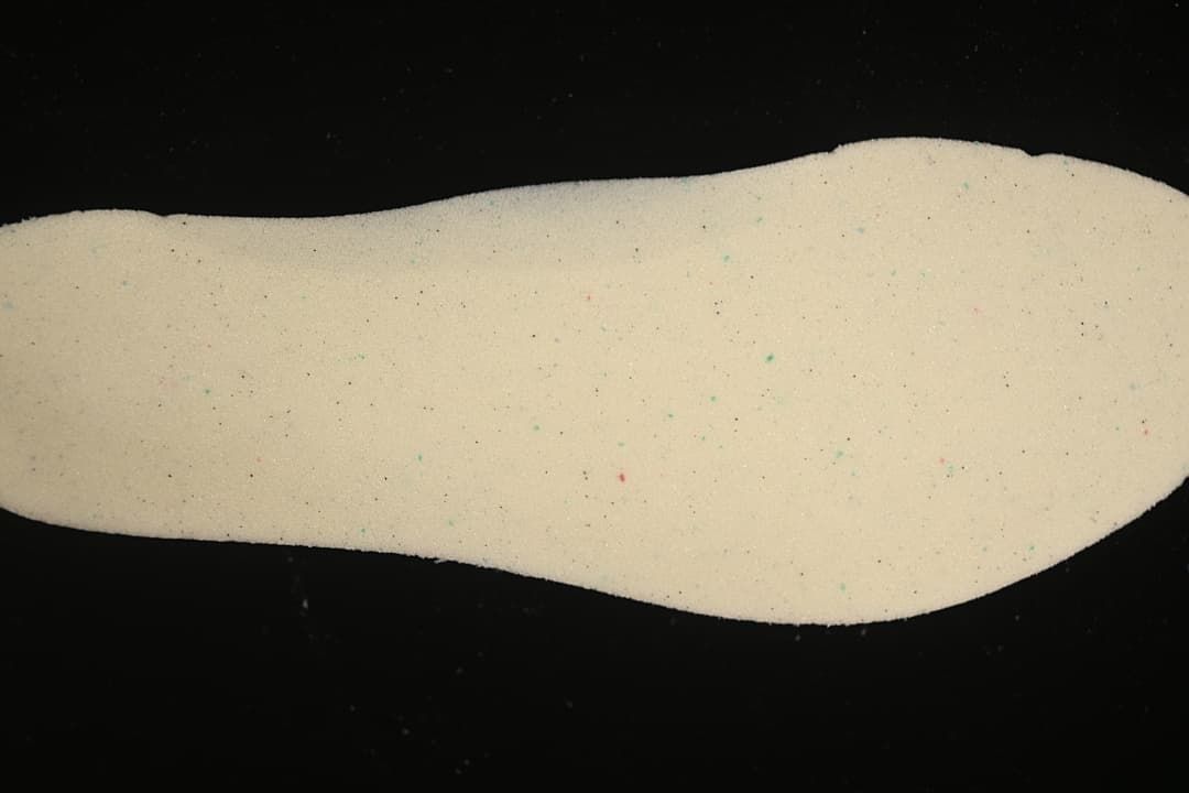 Close-up of a light-colored shoe insert shown against a dark background.